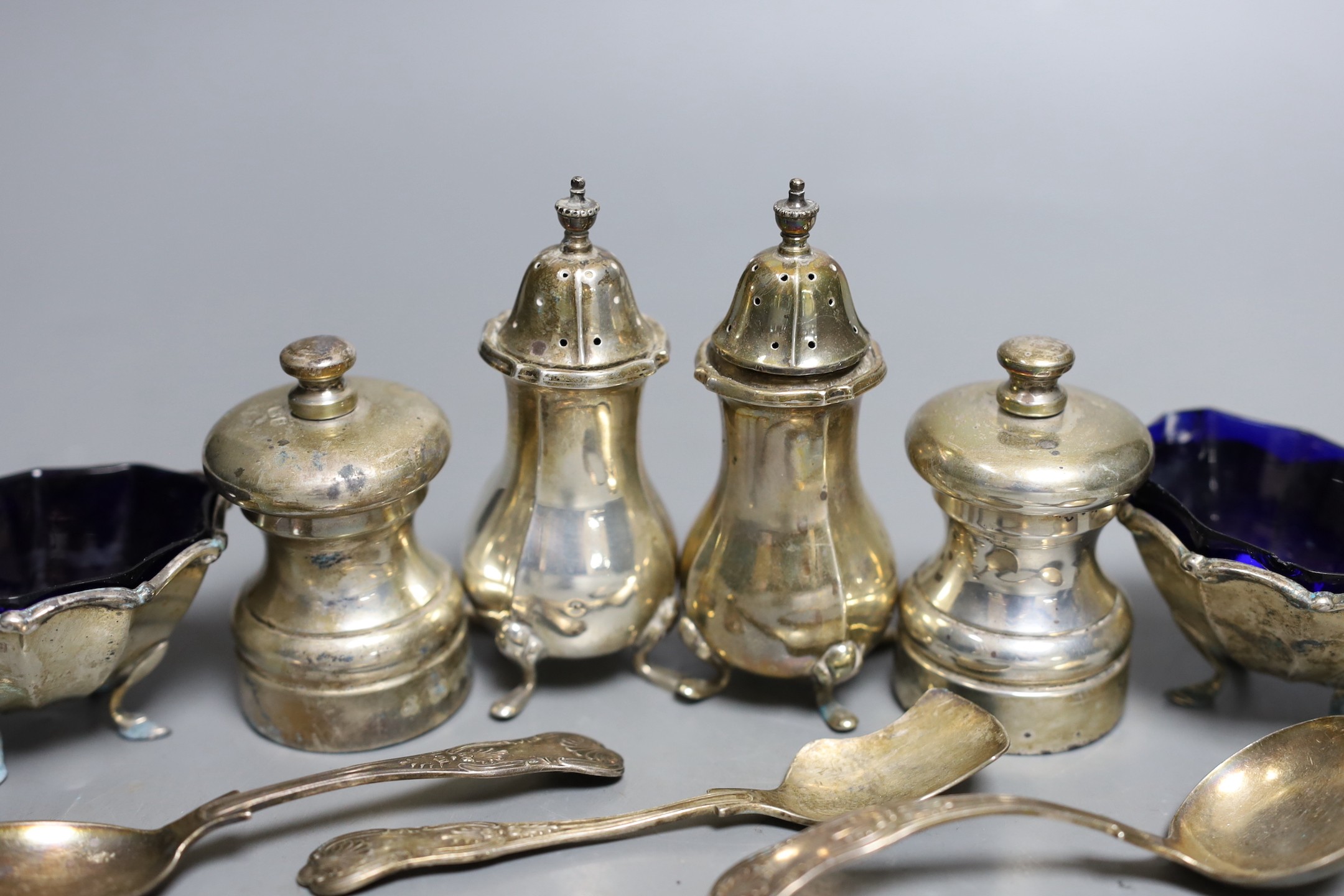 A modern pair of silver capstan shaped pepper mills, a pair of silver salts and pepper pots, a pair of matching salts and three various spoons.